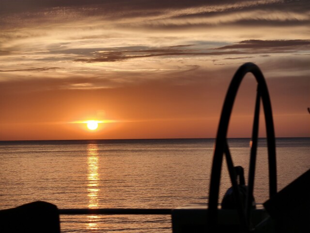 Sunset at the helm during a yacht transfer passage – SailorOne